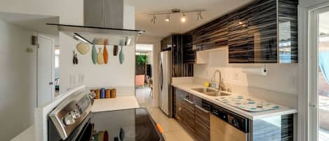 A modern kitchen with a stove, oven, and sink. There is a window with a view of the outdoors.