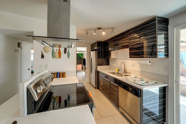 Cocina moderna con estufa, horno y lavamanos. Se aprecia una ventana con vistas al exterior.
