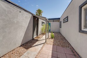 Un estrecho sendero que lleva a la entrada de un edificio, con una puerta y un pequeño ventanal.