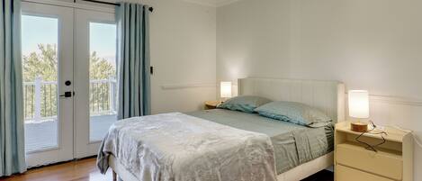 A bedroom with a bed, a nightstand, a lamp, and a sliding glass door.