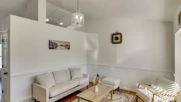 A living room with a white sofa, a wooden coffee table, a white armchair, and a hanging light fixture.