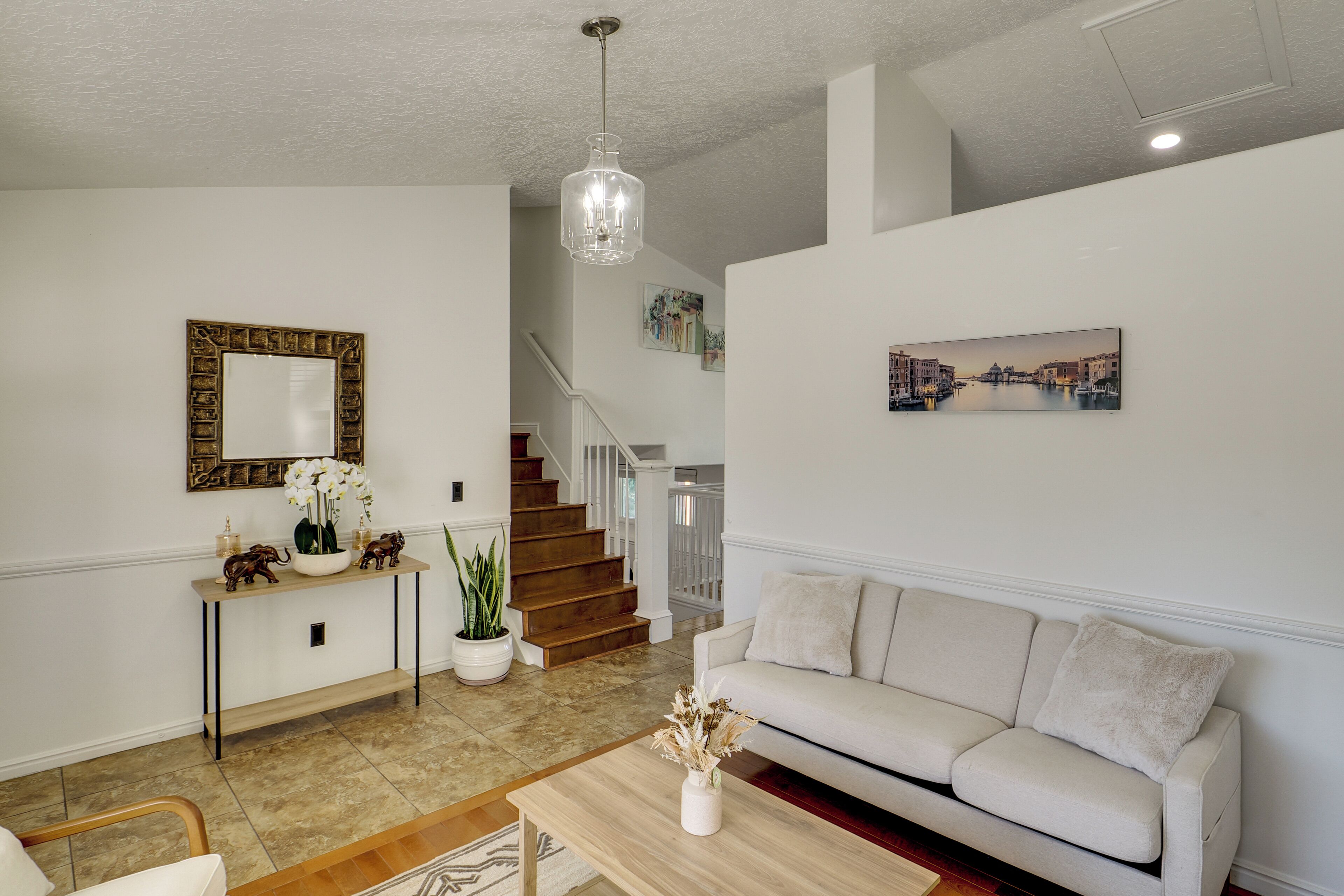 A spacious living area with a sofa, a coffee table, a staircase, and a hallway leading to another room.