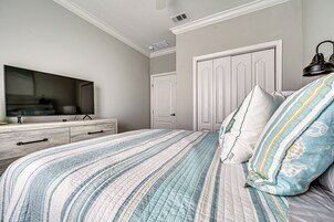 Un dormitorio con una cama, un televisor sobre un aparador y una puerta.