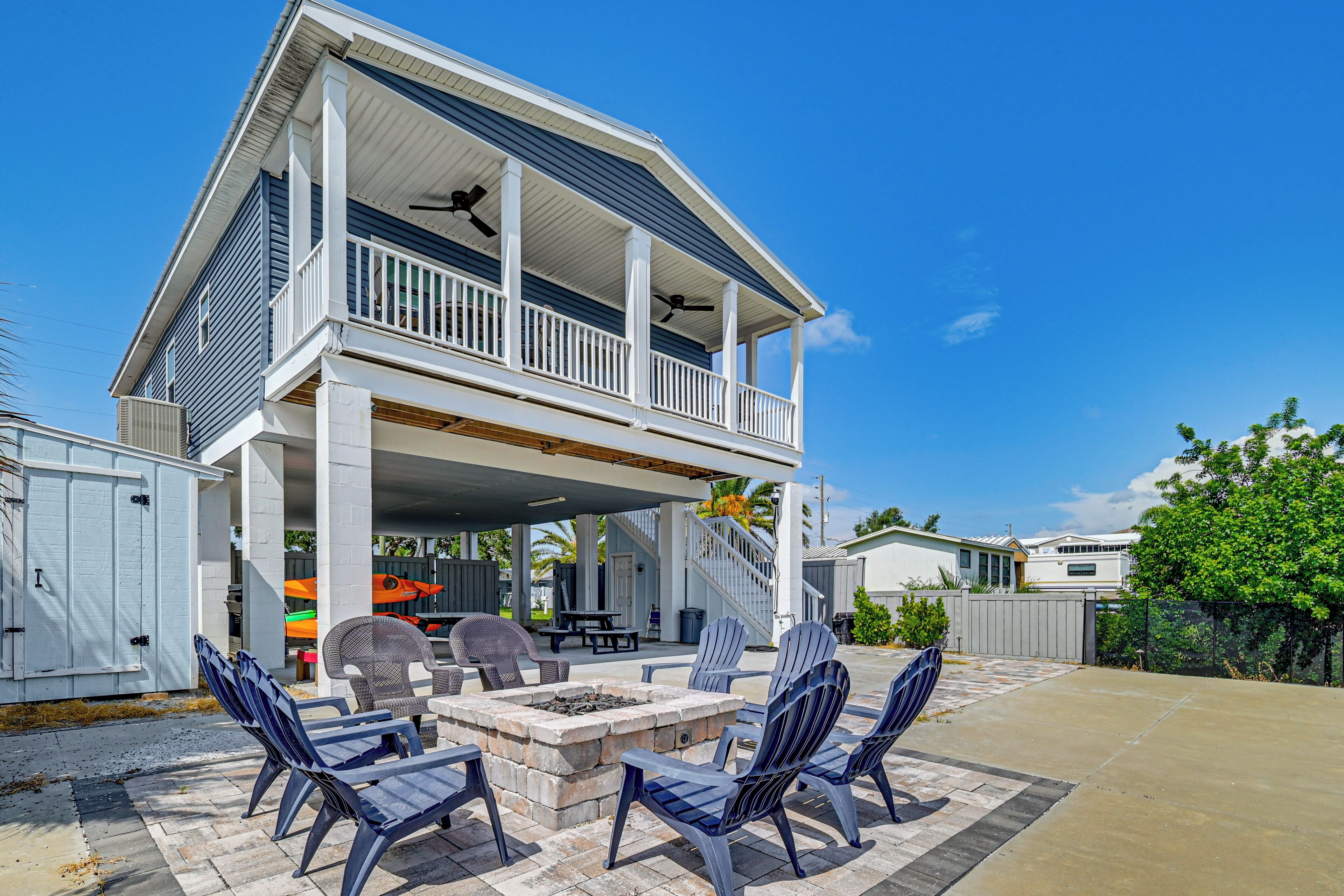 A two-story house with a covered patio area featuring outdoor furniture and a fire pit.