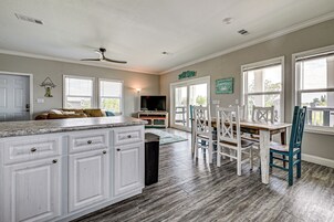 A spacious kitchen with white cabinetry, a wooden dining table, and a ceiling fan.
