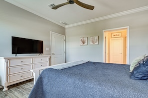 Un dormitorio con cama, cómoda, televisor y una puerta.