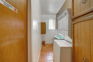 A laundry room with a washing machine, dryer, and a wooden cabinet. - Backyard Oasis! Spacious Tulsa Home w/ Pool (Tulsa)