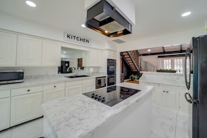 Una cocina moderna con armarios blancos, una isla central y un cartel que dice 'KITCHEN'.