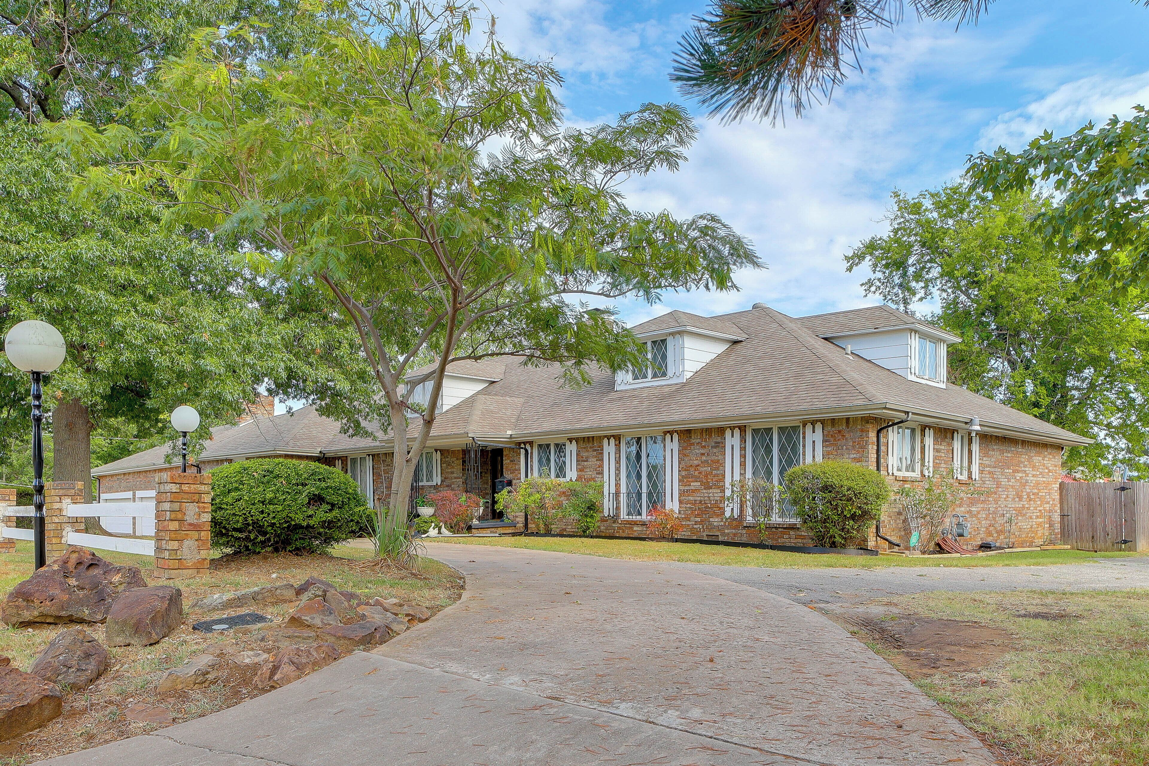 A two-story house with a brick facade, a covered front porch, and a driveway leading to the entrance.