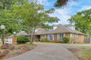 A two-story house with a brick facade, a covered front porch, and a driveway leading to the entrance. - Backyard Oasis! Spacious Tulsa Home w/ Pool (Tulsa)