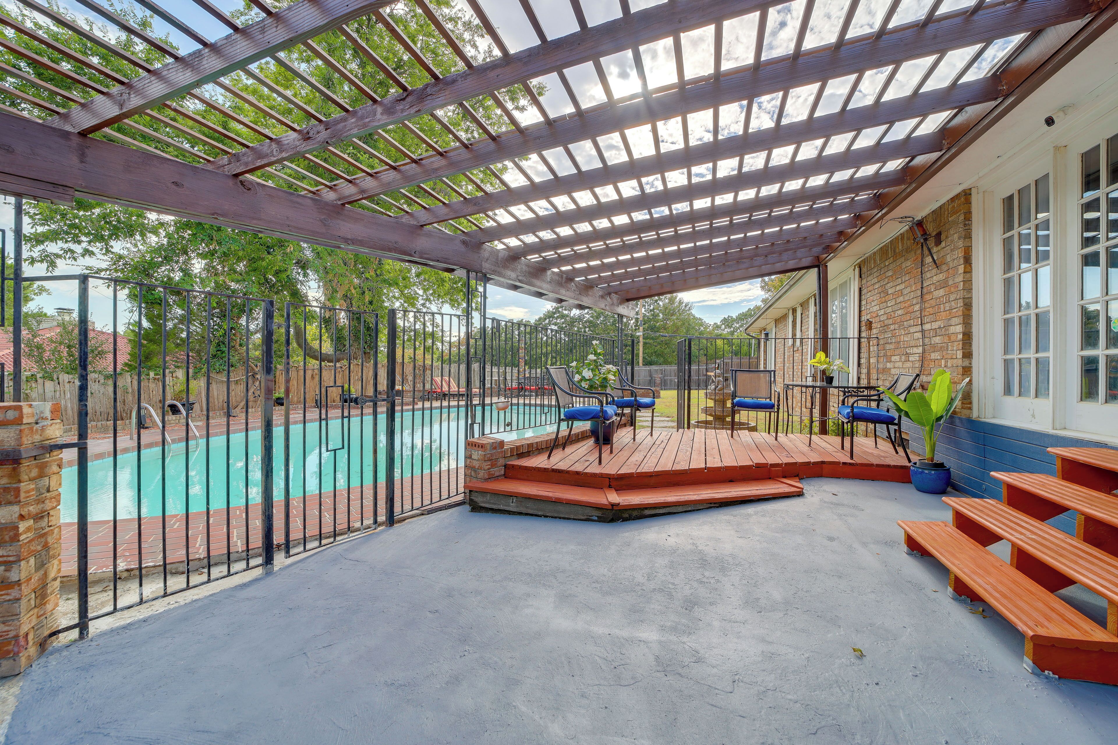 A covered outdoor area with a pool, seating, and a pergola.
