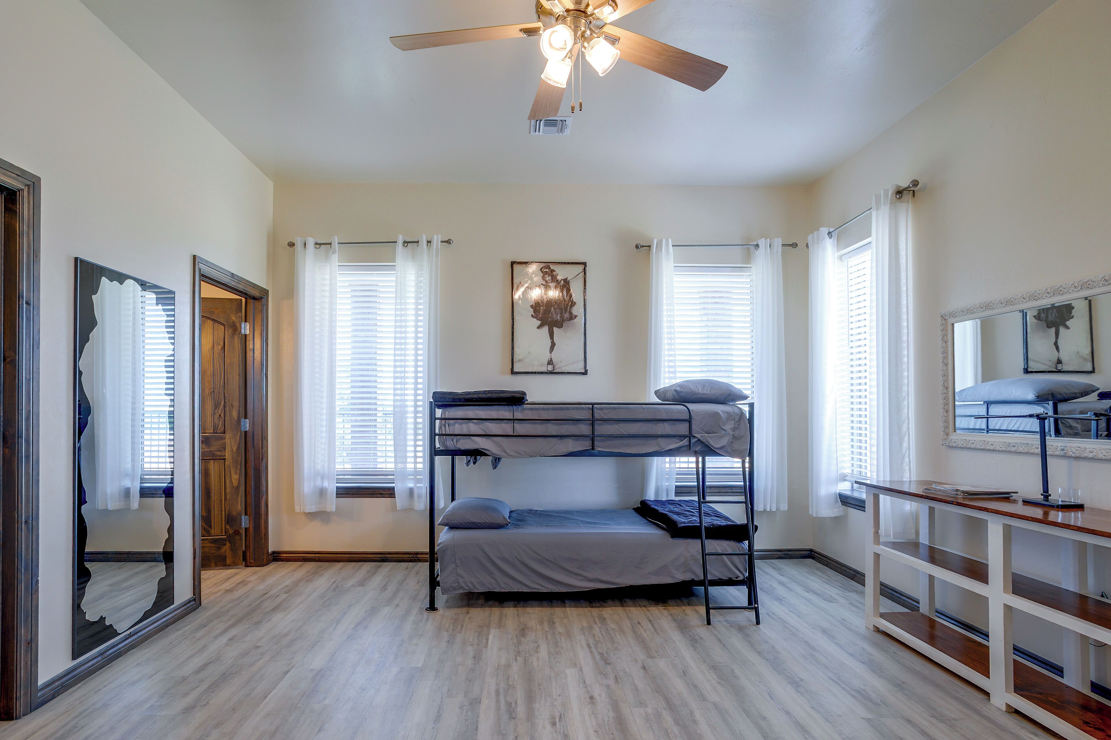 A dormitory room with bunk beds, a ceiling fan, and a mirror.