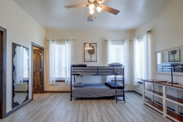A dormitory room with bunk beds, a ceiling fan, and a mirror.