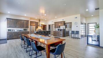A spacious kitchen with modern appliances, a dining area with a long table and chairs, and a separate dining area with a bar.