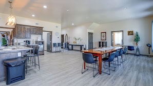 Una cocina amplia con una isla central, un comedor con una mesa y sillas largas, y una sala de estar con chimenea.