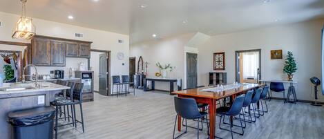 A spacious kitchen with a central island, a dining area with a long table and chairs, and a living area with a fireplace.