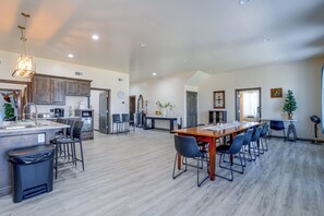 A spacious kitchen with a central island, a dining area with a long table and chairs, and a living area with a fireplace.