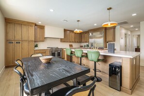 A modern kitchen with wooden cabinets, a central island with bar stools, and stainless steel appliances. - Private Home w/ Golf Course Views & Pool in Mesa! (Mesa)