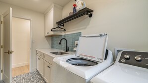 Une buanderie équipée d’un lave-linge, d’un sèche-linge, d’un évier et d’un étendoir.