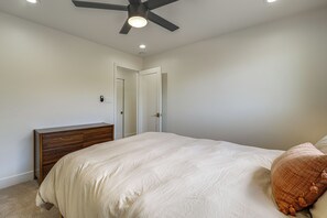 Ein Schlafzimmer mit Bett, Nachttisch, Deckenventilator und einer Tür.