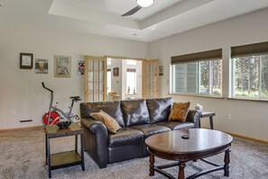 A spacious living room with a leather sofa, a coffee table, and a bicycle. - Exquisite Private Home Retreat Near Kenai River (Soldotna)