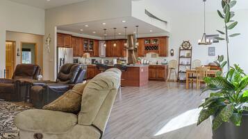 A spacious living room with a leather sofa, a dining area with wooden chairs, and a kitchen with wooden cabinets and stainless steel appliances.