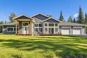 A two-story house with a covered porch, a garage, and a well-maintained lawn. - Exquisite Private Home Retreat Near Kenai River (Soldotna)
