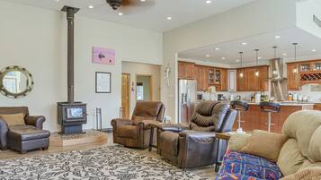 A spacious living room with a fireplace, leather sofas, a patterned rug, and a kitchen in the background.