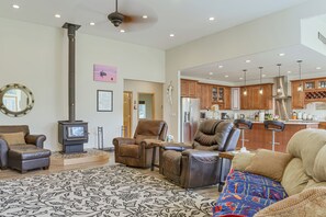 A spacious living room with a fireplace, leather sofas, a patterned rug, and a kitchen in the background.