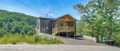 A cabin with a wooden exterior, a front porch, and a driveway leading to the entrance.