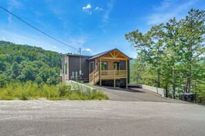 A cabin with a wooden exterior, a front porch, and a driveway leading to the entrance. - Brand-new Smokies Cabin w/ Spectacular Mtn Views (Sevierville)