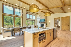A spacious kitchen with a large island, wooden cabinets, and a stone backsplash. - Brand-new Smokies Cabin w/ Spectacular Mtn Views (Sevierville)