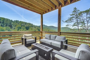 An outdoor deck with a sofa set and a fire feature, overlooking a forested landscape. - Brand-new Smokies Cabin w/ Spectacular Mtn Views (Sevierville)