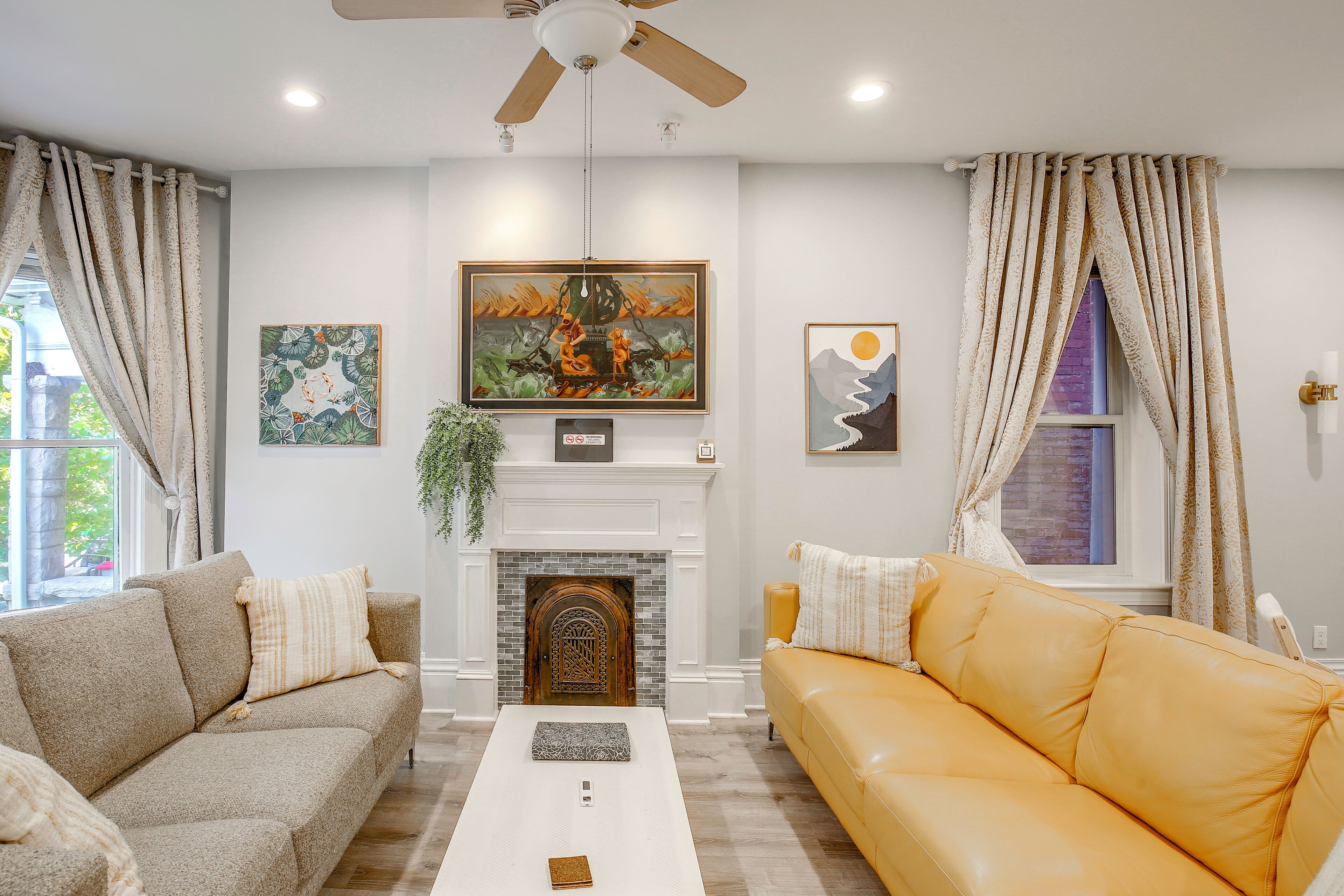 A living room with a fireplace, two sofas, and artwork on the walls.