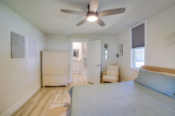 A bedroom with a bed, a chair, a wardrobe, and a ceiling fan.