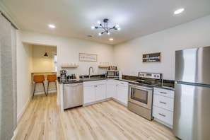 A modern kitchen with white cabinetry, stainless steel appliances, and a central island.