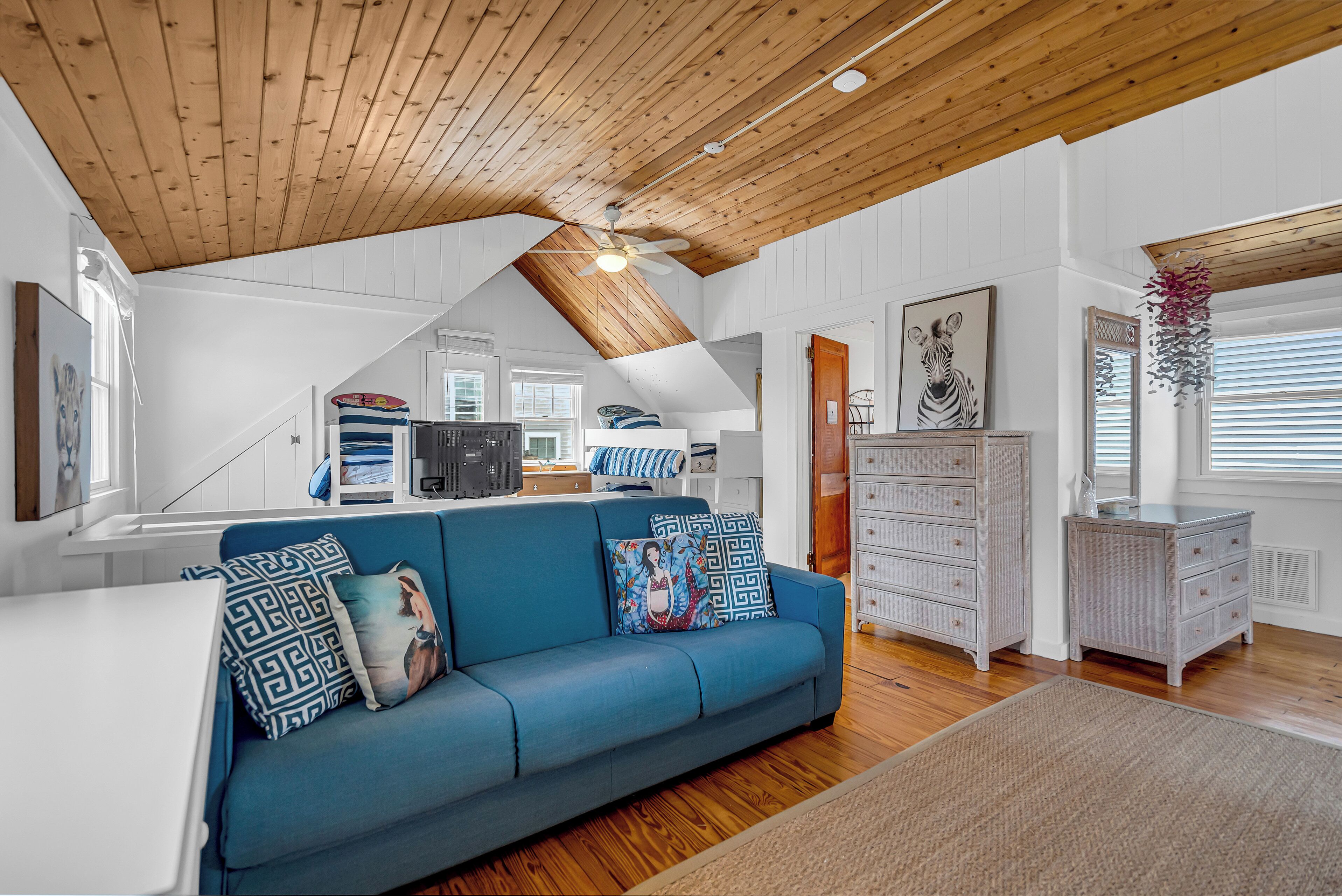 Un salón amplio con un sofá azul, techo de madera y paredes blancas.