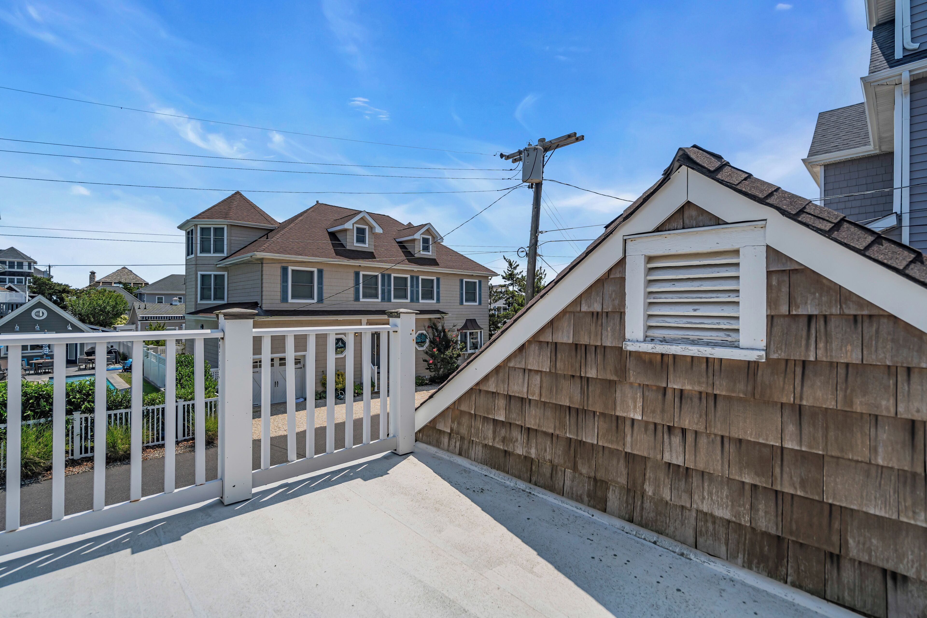 A residential property with a fenced backyard, a wooden deck, and a house with a gabled roof.