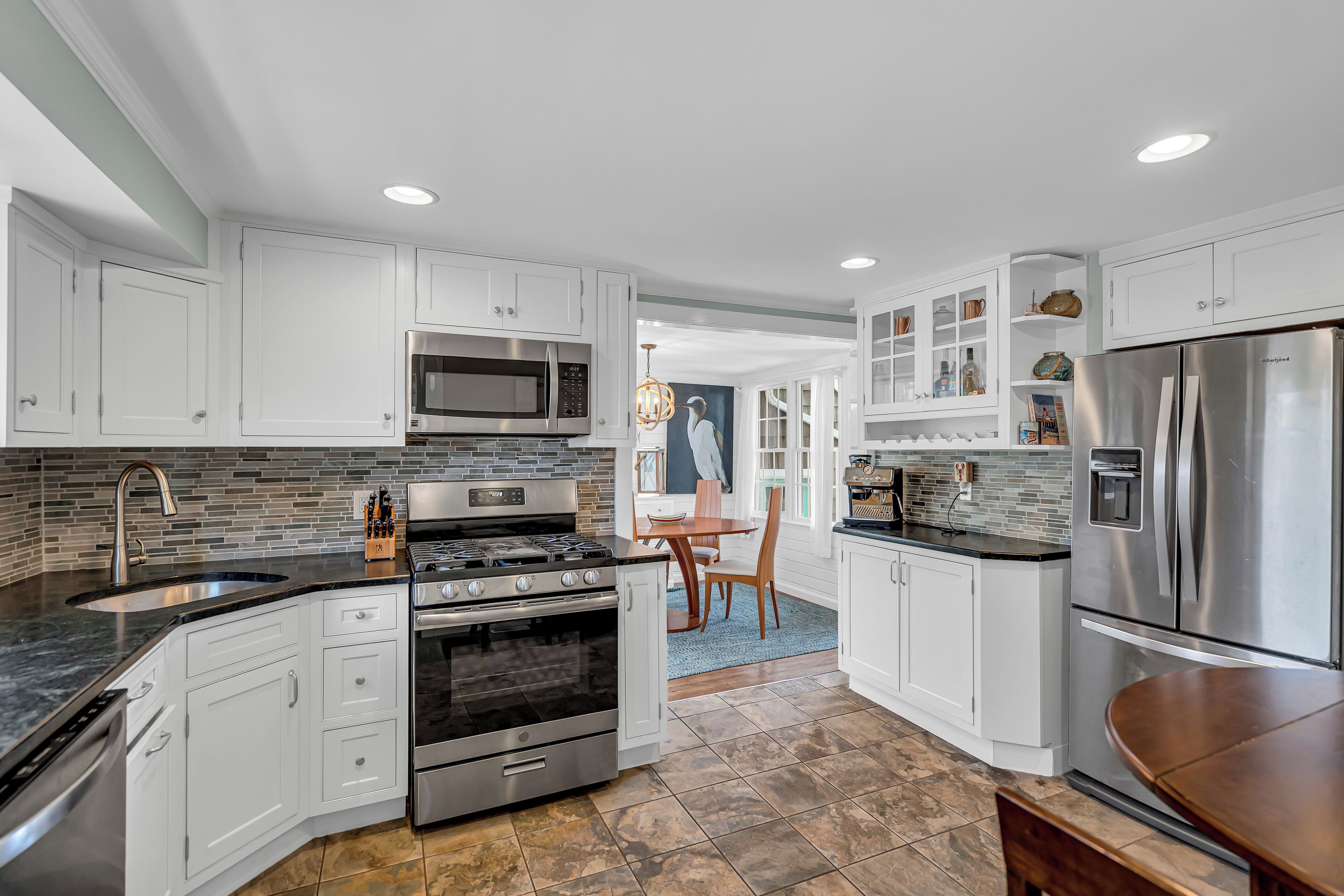 A modern kitchen with white cabinets, stainless steel appliances, and a tiled backsplash.
