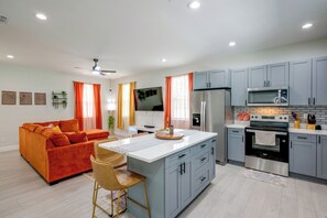 A modern kitchen with grey cabinets, a stainless steel refrigerator, and a microwave.