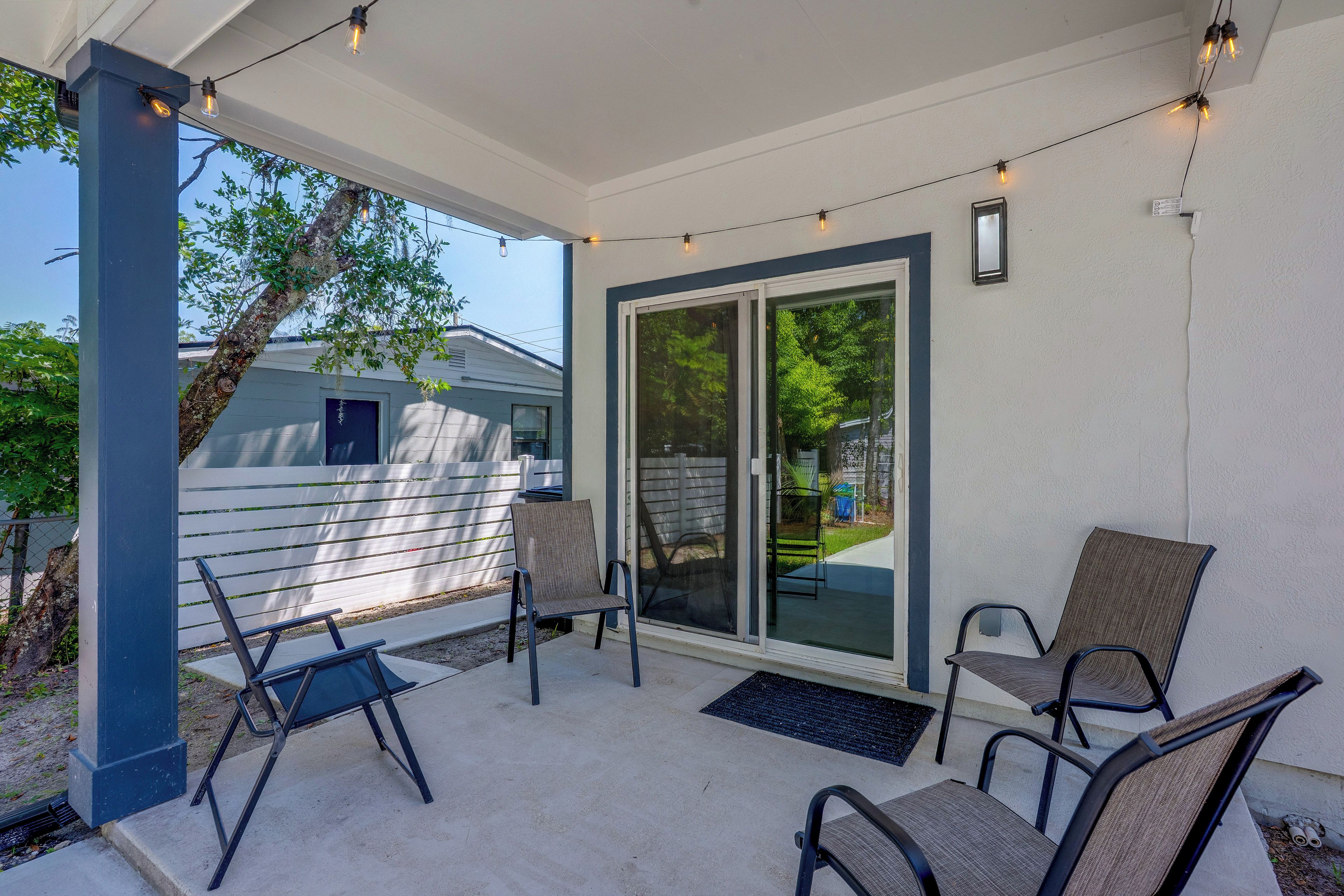 A covered patio area with a seating arrangement, a sliding glass door, and string lights.