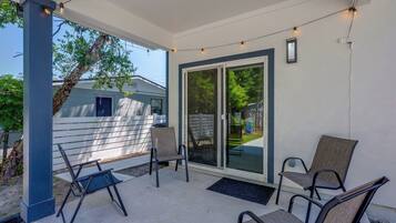 A covered patio area with a seating arrangement, a sliding glass door, and string lights.