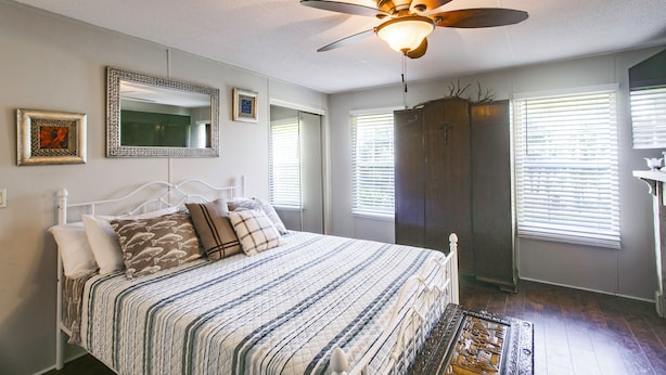 Un dormitorio con cama, ventilador de techo, armario y ventana con persianas.