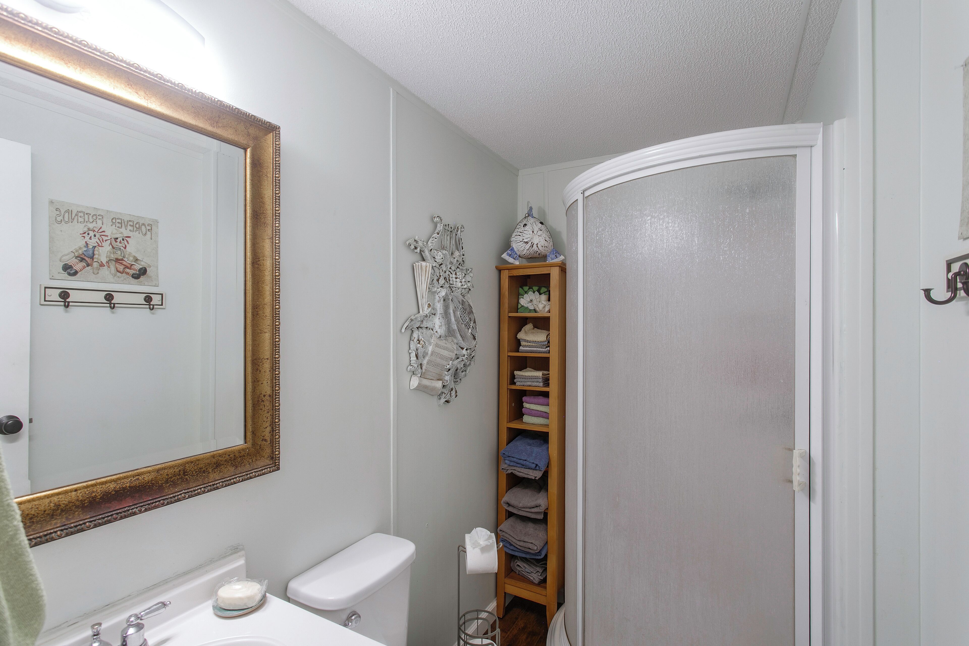 A bathroom with a white toilet, a sink with a mirror, and a towel rack.