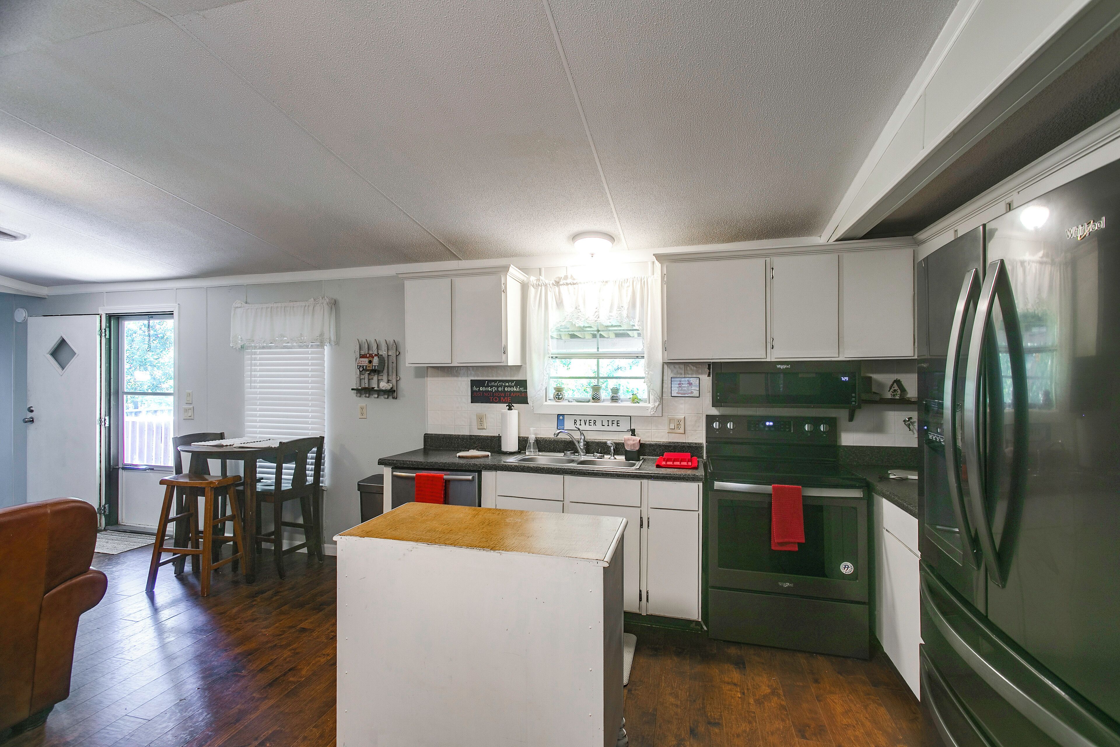 A compact kitchen with a refrigerator, stove, and microwave. There is a dining area with a table and chairs.