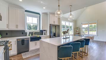 A modern kitchen with a large island, bar stools, and a view of the outdoors.
