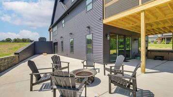 A modern house with a covered patio area featuring outdoor furniture and a grill.