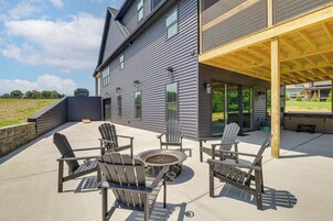 A modern house with a covered patio area featuring outdoor furniture and a grill.