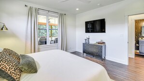Een slaapkamer met een bed, een dressoir, een televisie en een plafondventilator.