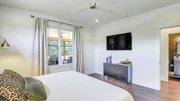 A bedroom with a bed, a dresser, a television, and a ceiling fan.
